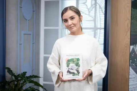 Kobieta w białym swetrze trzyma książkę "Tak działa mózg". To uwaga definicja, jak działa nasz umysł.