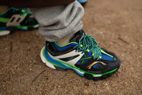 Sneaker Balenciaga con suola chunky, significato di stile audace e comfort. Lacci verdi vivaci su nero, blu e bianco.