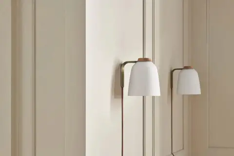 Elegancka lampa klinkiet z białym, plisowanym kloszem i drewnianą nakładką, subtelnie oświetla wnętrze.