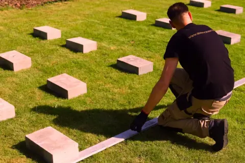 Pracownik układa bloczki betonowe pod przyszły domek.