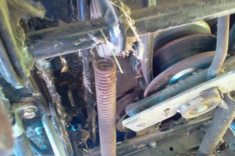 Mechanizm kosiarki traktorka MTD z widocznym pasem, sprężyną i kołami pasowymi. Pomoc w zrozumieniu, jak założyć pasek do kosiarki traktorka MTD.