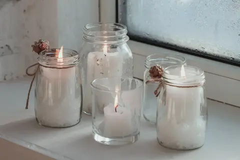 Fünf Windlichter mit Kerzen, die zum Windlicht selber machen inspirieren. Dekoriert mit Zapfen und Juteband.
