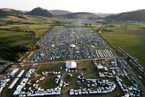Vasto accampamento di tende e camper per il festival celtico Montelago, immerso in un paesaggio collinare verdeggiante.