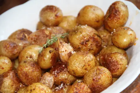 Un plat de pommes de terre grenaille au four, dorées et croustillantes, parsemées de sel et d'herbes.