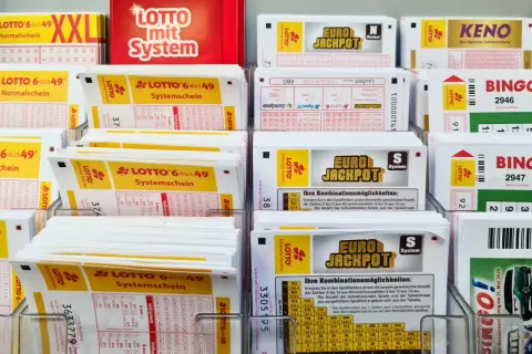 Stojaki z kuponami lotto, w tym Eurojackpot, Lotto 6 aus 49 i Keno.