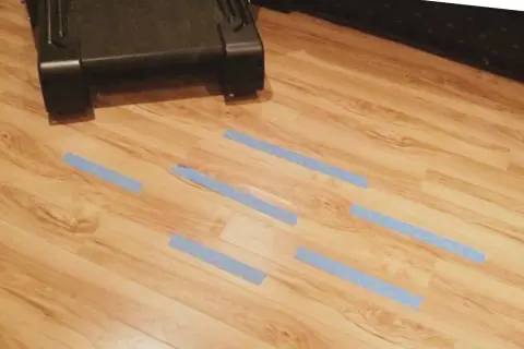 Marcando con cinta azul las áreas del parquet dañado por humedad para repararlo.