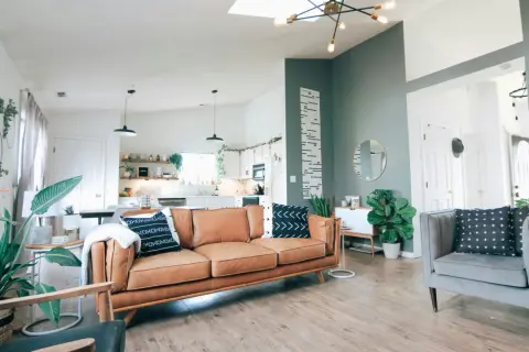 Wygodny salon z dwoma sofami zamiast narożnika, brązową i szarą, ozdobiony roślinami i geometrycznymi poduszkami.