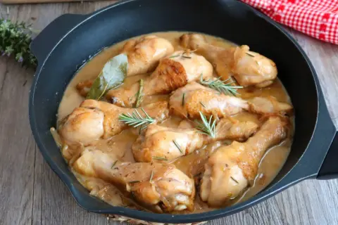 Jamoncitos de pollo guisados en una sartén, con hierbas aromáticas y una salsa cremosa. ¡Un plato casero delicioso!