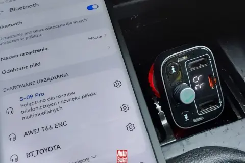 Samochodowy transmiter FM z Bluetooth, połączony z telefonem. Widoczny ekran telefonu z ustawieniami Bluetooth i sparowanymi urządzeniami.