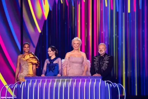 Cztery osoby na scenie z kolorowym tłem. Jedna z nich, w złotej sukni, może reprezentować Polskę na Eurowizji.