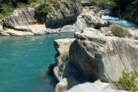 Aguas turquesas fluyen entre rocas erosionadas. Un lugar idílico para leer reseñas de la poza del molino y disfrutar de la naturaleza.