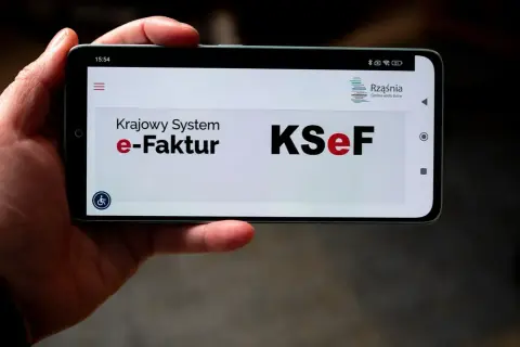 Dłoń trzyma smartfon z widocznym ekranem logowania do KSeF. Użytkownik napotyka problem z logowaniem do Krajowego Systemu e-Faktur.