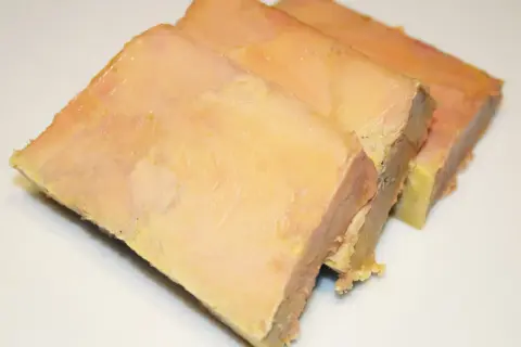 Trois tranches de terrine de foie gras, préparées avec une presse, sur fond blanc.
