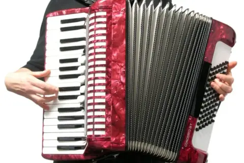 Czerwony akordeon instrument, z klawiaturą i miechem, gotowy do gry.
