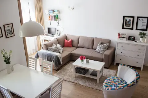 Przytulny salon z narożnikiem, stołem i biurkiem. Układ mieszkań w bloku z wielkiej płyty zaaranżowany na nowo.