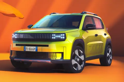 Jaskrawożółty fiat elektryczny z nowoczesnym designem, gotowy na letnią przygodę pod pomarańczowym parasolem.