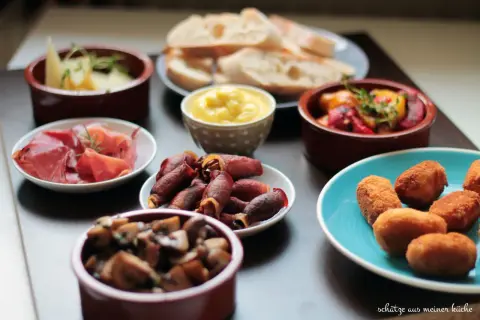 Vielfalt an Tapas: Käse, Schinken, Pilze, gefüllte Datteln im Speckmantel, Kroketten und Brot. Ein Fest für die Sinne!