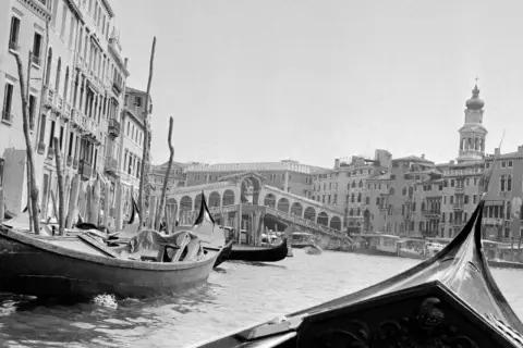 Gondole a Venezia, un classico scatto di Inge Morath. Il Ponte di Rialto sullo sfondo, con edifici storici e il Canal Grande.