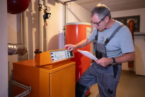 Tecnico controlla la caldaia, documentazione alla mano, per stimare il costo manutenzione caldaia.