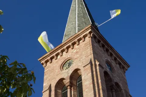Kirchturm mit Fahnen im Wind, ein Zeichen, dass die Kirchweih gefeiert wird.