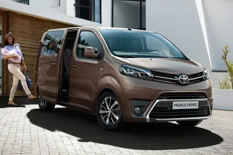 Kobieta z dzieckiem na rękach wsiada do brązowego toyoty van Proace Verso.