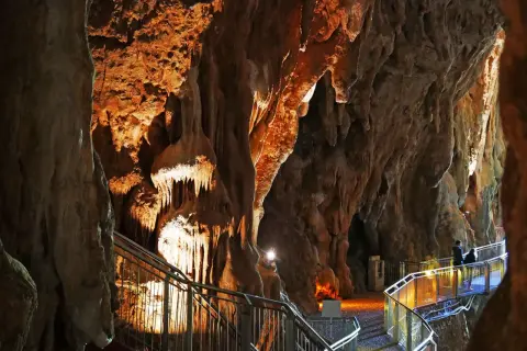 Sentiero illuminato tra le stalattiti delle grotte di Pastena, con persone che passeggiano.
