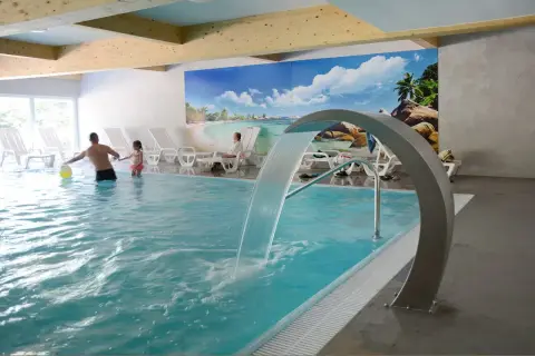 Rodzina bawi się w basenie z wodospadem w hotelu Pokrzywna. Relaks w gorzelnianym klimacie.