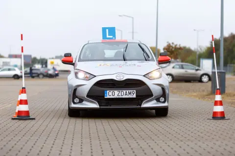 Samochód nauki jazdy z literą "L" na dachu i tablicą "CO ZDAM9". Czy po zdaniu egzaminu na prawo jazdy można jeździć samochodem?
