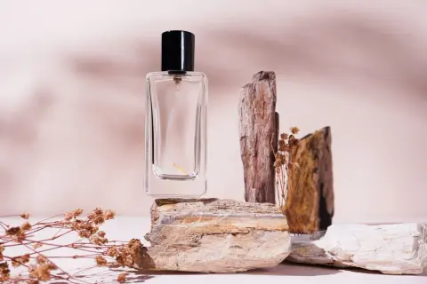 Szklana buteleczka perfum na kamieniach, otoczona suchymi gałązkami. Zapach niczym mocno pudrowe perfumy, delikatny i subtelny.