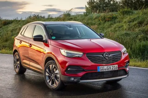 Czerwony Opel Grandland X na mokrej drodze. Wiele pozytywnych opinii o tym modelu.