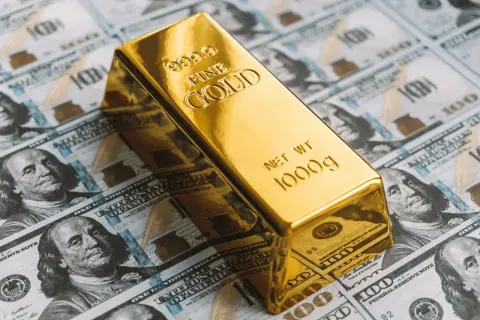 Lingote de oro de 1000g sobre billetes de cien dólares. ¿Cuánto vale 1 kg de oro?