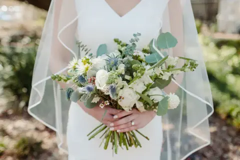 Panna młoda trzyma bukiet ślubny, w którym zastosowano technikę watowania we florystyce. Kwiaty są ułożone w luźny, naturalny sposób.