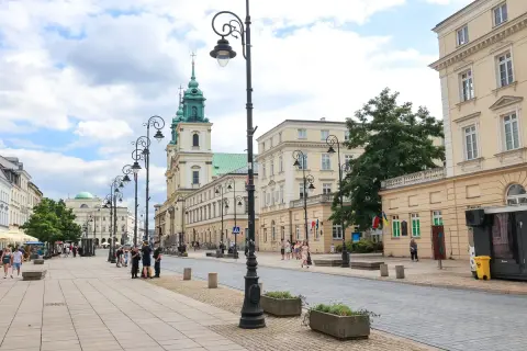 Spacer po Krakowskim Przedmieściu w Warszawie, z zabytkowymi kamienicami i kościołem w tle.