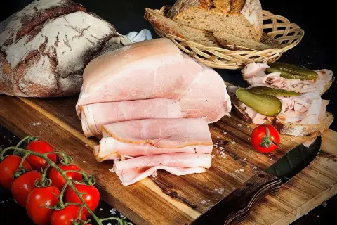 Frisch aufgeschnittener Kochschinken, der Lust macht, ihn selber zu machen. Dazu Brot, Tomaten und Gewürzgurken.