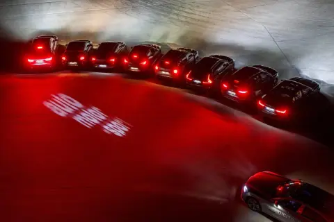 En rad bilar med tända bakljus lyser upp mörkret. Lampor i bilen skapar ett dramatiskt sken.