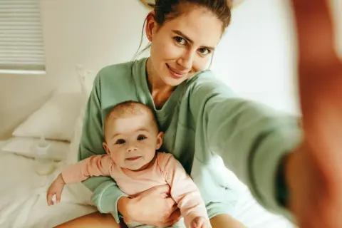 Uśmiechnięta mama z dzieckiem na rękach, czuje, kiedy macierzyństwo zaczyna cieszyć.