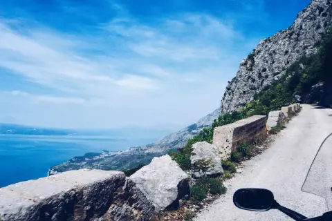 Widok z motocykla na krętą drogę w Chorwacji, z widokiem na morze i góry. Niezapomniana podróż!
