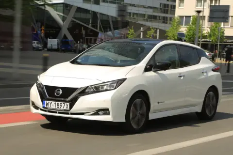 Biały Nissan Leaf 2 jedzie ulicą miasta.