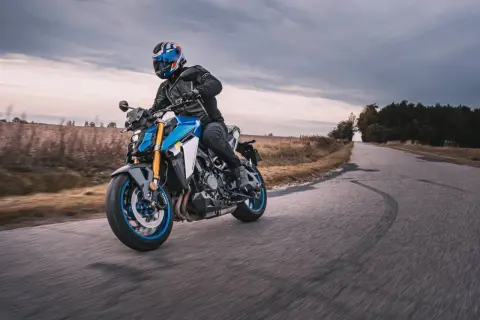 Motocyklista w kasku z brytyjską flagą pokonuje zakręt na drodze, doświadczając zjawiska shimmy.