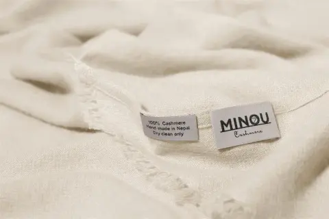 Miękka, kremowa paszmina z metkami: "100% Cashmere, Hand made in Nepal, Dry clean only" i "MINOU Cashmere".