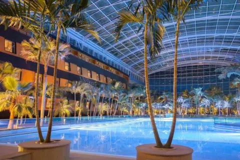 Tropikalny raj w Termach Erding: basen pod szklanym dachem, palmy i hotel.
