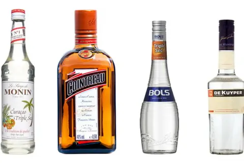 Cztery butelki likierów: Monin, Cointreau, Bols Triple Sec i De Kuyper. Cointreau to znany likier pomarańczowy, a Bols Triple Sec to jego tańsza alternatywa.