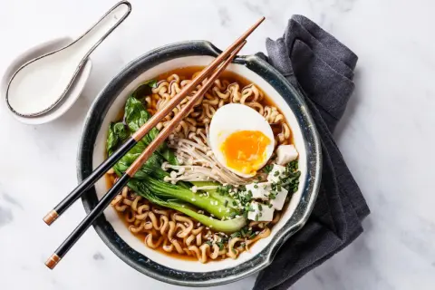 Eine dampfende Schüssel mit köstlicher Ramen-Suppe, garniert mit einem perfekt gekochten Ei, Tofu und Gemüse.