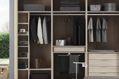 Un armario moderno y funcional, ideal para quienes buscan cómo diseñar un armario con estilo. Ropa colgada, cajones y estantes organizados.