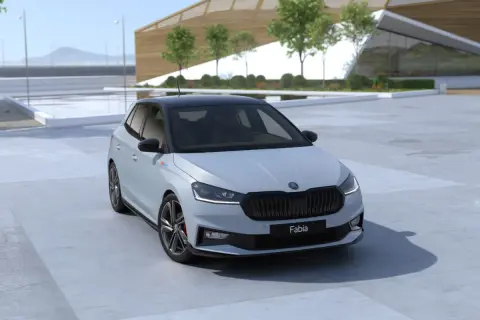Nowa Skoda Fabia 2026 w jasnym kolorze z czarnym dachem, zaparkowana przed nowoczesnym budynkiem.