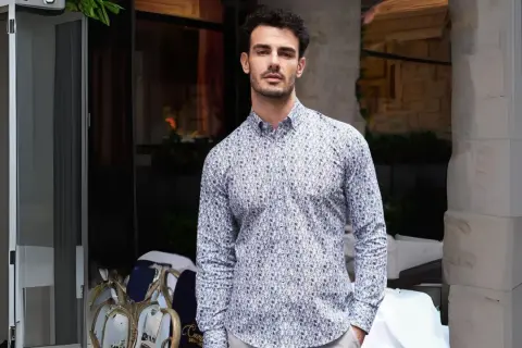 Uomo con camicie di tendenza uomo con fantasia astratta, in piedi all'esterno di un locale.
