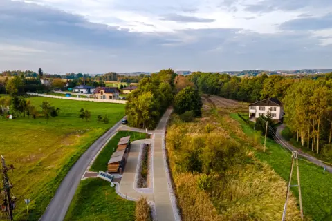 Krajobraz z Gołkowic: domy, droga, ścieżka rowerowa i las.