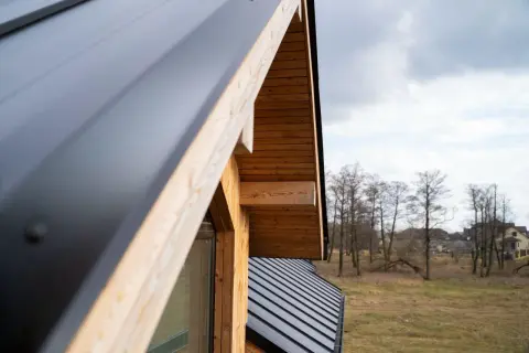 Detalle de cómo hacer un tejado de madera a un agua, con estructura de madera y cubierta metálica oscura.