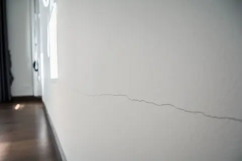 Pęknięcie na białej ścianie, widoczne w zbliżeniu.