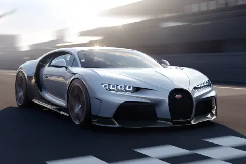 Srebrny Bugatti Chiron Super Sport pędzi po torze wyścigowym, jego światła LED błyszczą w słońcu.